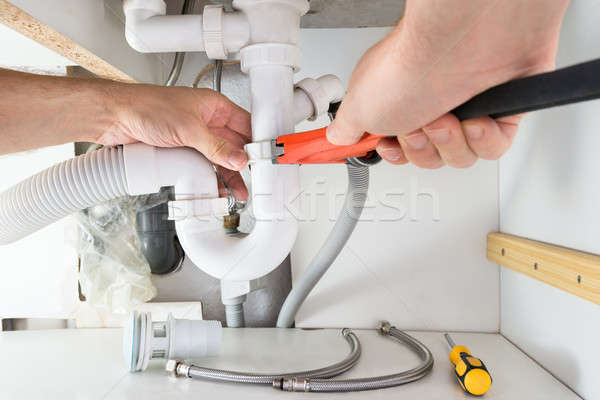 Stock photo: Male Plumber Fixing Sink In Bathroom