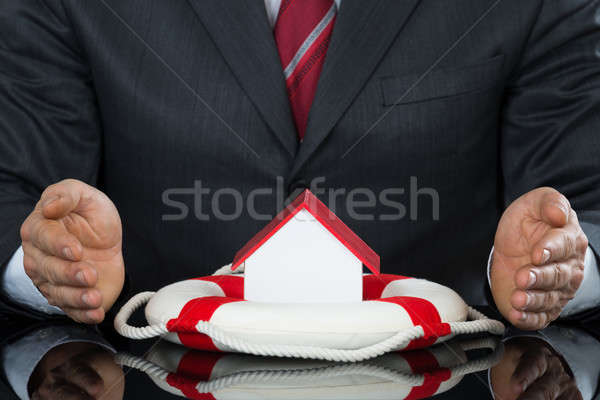 Businessman Hand Protecting House Model With Lifebelt Stock photo © AndreyPopov