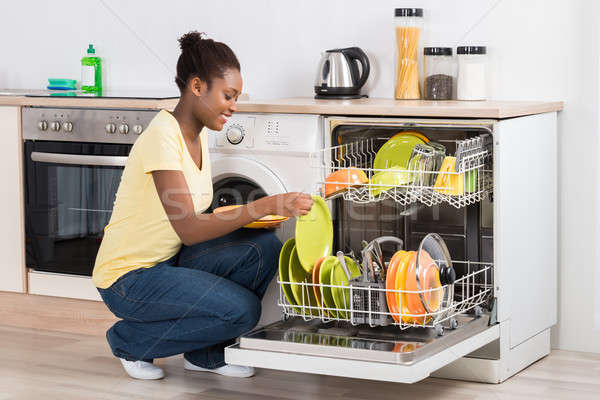 Happy Woman Arranging Plates In Dishwasher Stock photo © AndreyPopov
