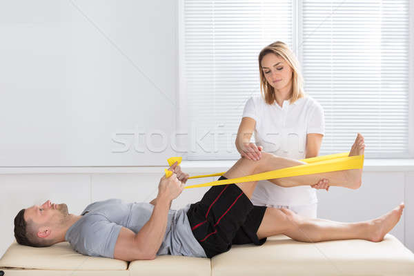 Man Training With Exercise Band Assisted By Physiotherapist Stock photo © AndreyPopov