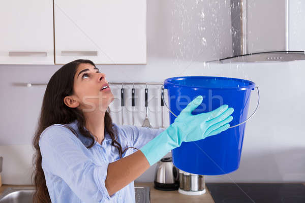 Woman Holding Bucket While Water Droplets Leak From Ceiling Stock photo © AndreyPopov