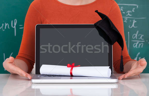 Student Showing Laptop With Mortarboard And Degree In Classroom Stock photo © AndreyPopov