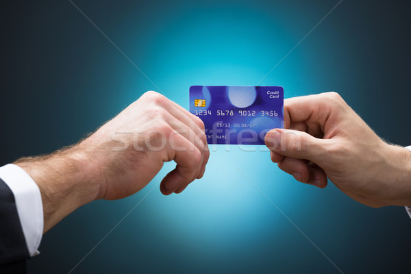 Businessmen Holding Credit Card Against Blue Background Stock photo © AndreyPopov