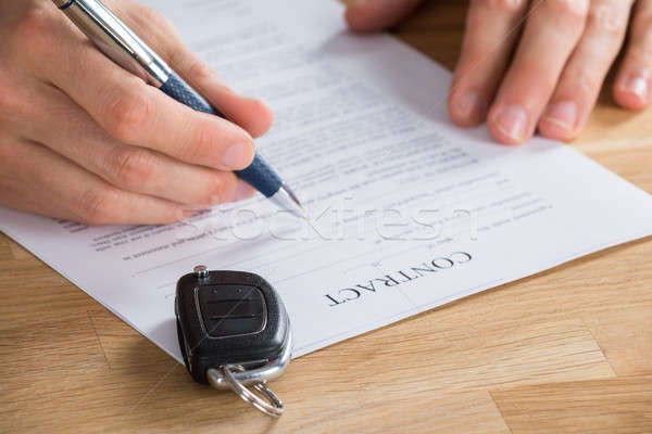 Stock photo: Businessperson Holding Pen On Contract With Car Key On It