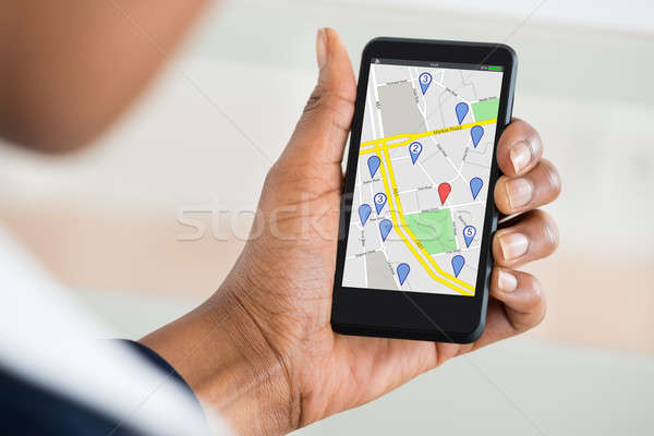 Woman's Hand Holding Mobile Phone With Location Mark On Map Stock photo © AndreyPopov