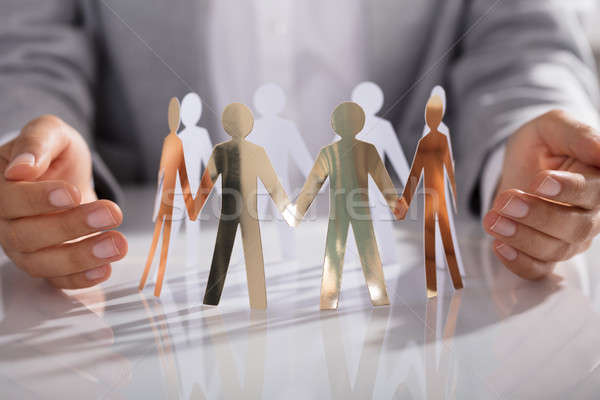 Businessperson Hand Protecting Paper Cut Out Figure On Table Stock photo © AndreyPopov