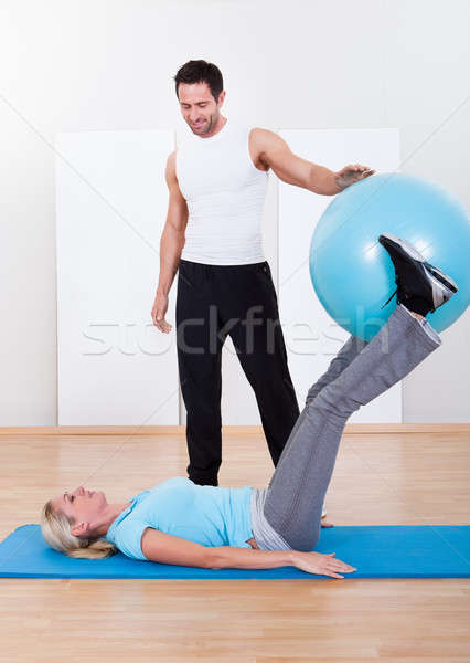 Instructor helping a woman with pilates exercises Stock photo © AndreyPopov