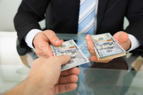 Businessman Passing Money To Colleague At Table Stock photo © AndreyPopov