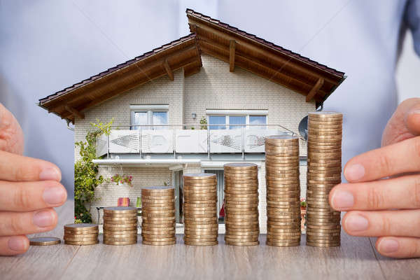 Man Securing House Model And Stack Of Coins Stock photo © AndreyPopov