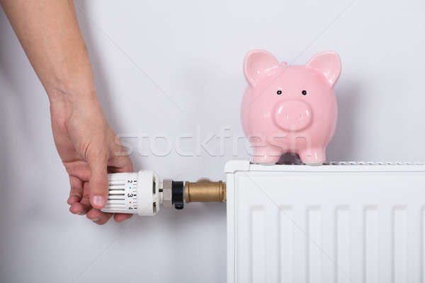 Mão termóstato piggy bank radiador parede Foto stock © AndreyPopov