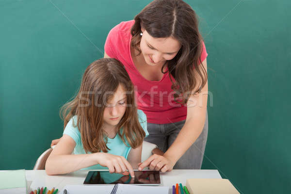 Teacher Assisting Girl In Using Digital Tablet Stock photo © AndreyPopov