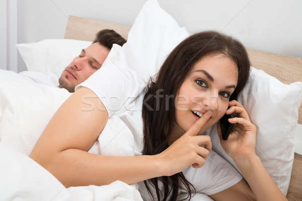 Nő beszél mobiltelefon férj alszik ágy Stock fotó © AndreyPopov