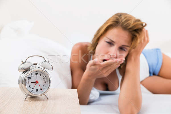 Woman With Alarm Clock On Nightstand Stock photo © AndreyPopov