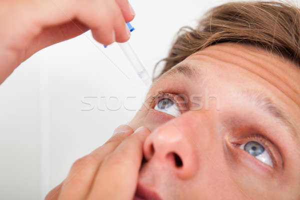 Young Man Putting Eye Drops In His Eyes Stock photo © AndreyPopov
