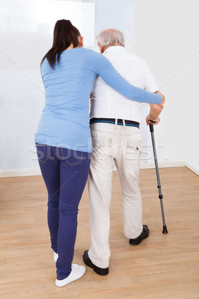 Caregiver Assisting Senior Man To Walk With Stick Stock photo © AndreyPopov