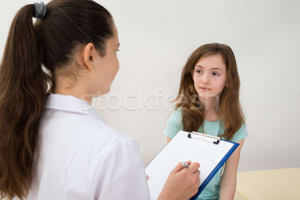 Doctor Writing On Clipboard In Front Of Patient Stock photo © AndreyPopov