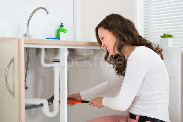 Woman Tightening Pipe Under Sink Stock photo © AndreyPopov