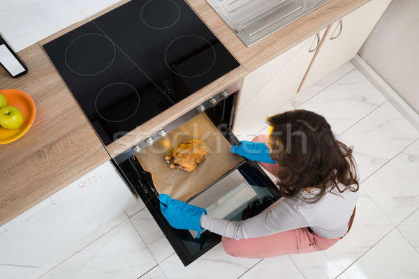 Woman Putting Chicken In Oven Stock photo © AndreyPopov