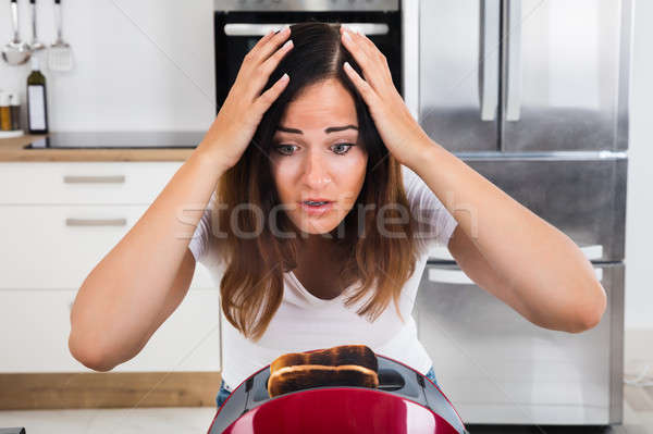 Frustrated Woman Looking At Burnt Toast In Toaster Stock photo © AndreyPopov