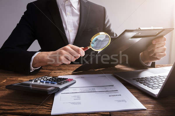 Homme d'affaires document loupe presse-papiers bois bureau Photo stock © AndreyPopov