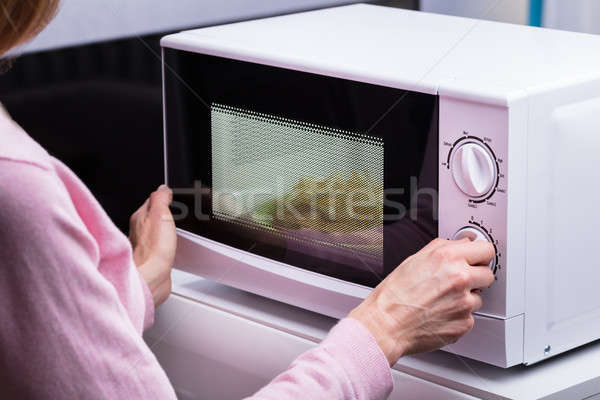 Vrouw magnetronoven oven verwarming voedsel Stockfoto © AndreyPopov