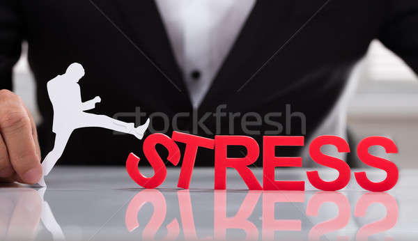 Businessperson holding human figure kicking stress word Stock photo © AndreyPopov