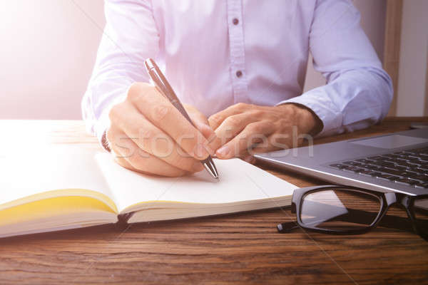Person's Hand Writing On Black Notebook Stock photo © AndreyPopov