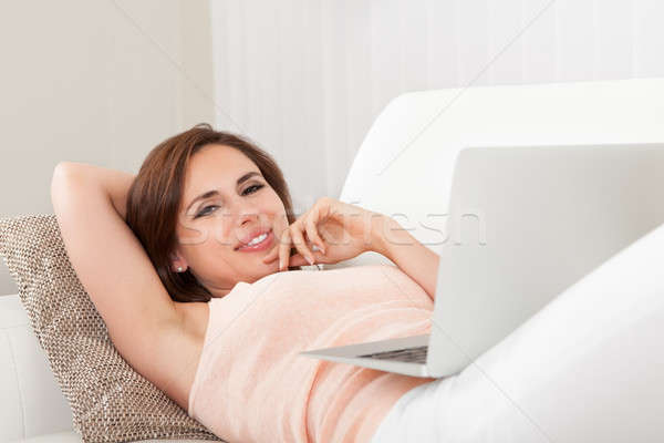 Fiatal nő laptop boldog nő kanapé mosoly Stock fotó © AndreyPopov