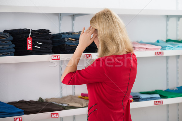 Confused Woman Gesturing While Looking At Clothes Stock photo © AndreyPopov
