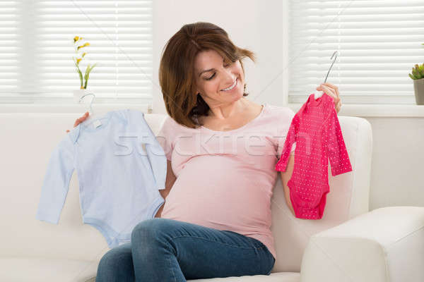 Stock photo: Pregnant Woman Holding Baby Clothes