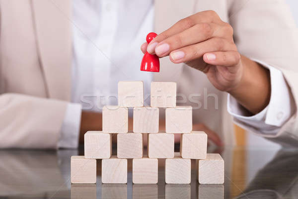 Stock photo: Businesswoman Placing Red Figure On Arranged Blocks