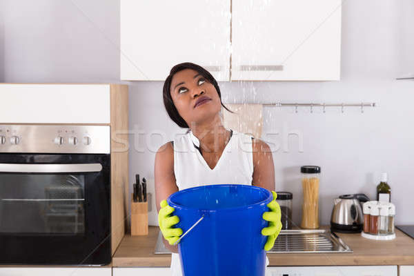 Woman Holding Bucket While Water Droplets Leak From Ceiling Stock photo © AndreyPopov