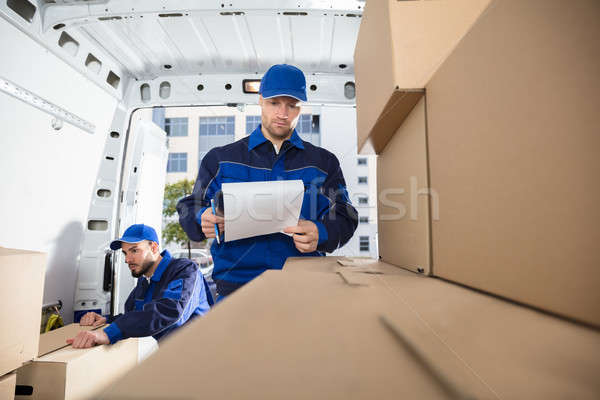 Mover Looking At His Partner Writing On Clipboard Stock photo © AndreyPopov