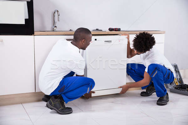 Two Handy Men Fixing The Dishwasher In The Kitchen Stock photo © AndreyPopov