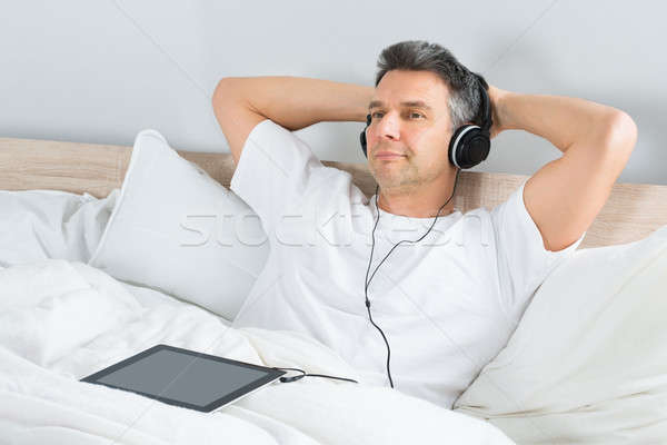 Hombre escuchar música auriculares adjunto tableta Foto stock © AndreyPopov