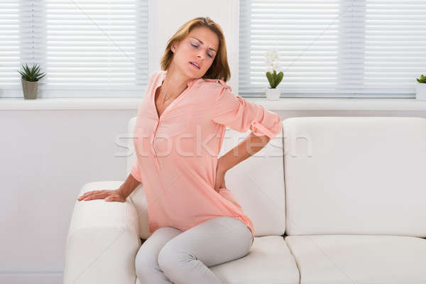 Kobieta sofa cierpienie ból w krzyżu młoda kobieta posiedzenia Zdjęcia stock © AndreyPopov