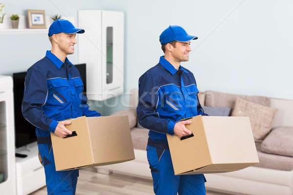 Two Delivery Man Carrying Cardboard Box In New Home Stock photo © AndreyPopov