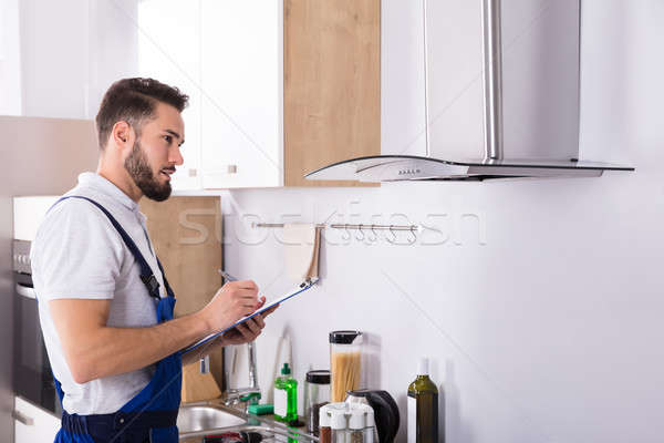 Technician Writing On Clipboard In Front Of Kitchen Extractor Stock photo © AndreyPopov