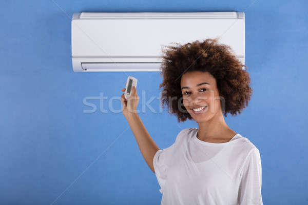 Mulher ar condicionado controle remoto mulher jovem azul parede Foto stock © AndreyPopov