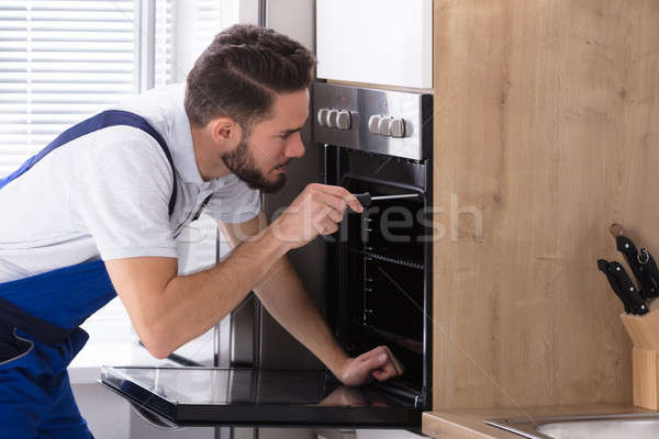 Stock photo: Electrician Repairing Oven With Screwdriver