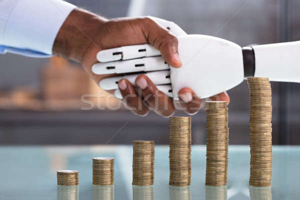 Man Shaking Hand With Robot With Coin Stack Stock photo © AndreyPopov