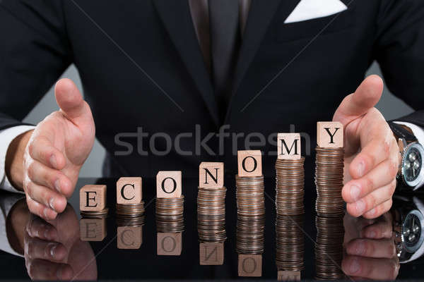 Businessman Protecting Economy Blocks On Stacked Coins Stock photo © AndreyPopov