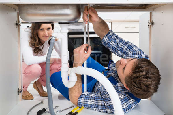 Worker Fixing Sink In Front Of Woman In Kitchen Stock photo © AndreyPopov