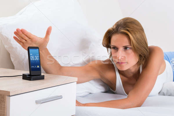 Woman Snoozing Alarm On Mobile Phone Stock photo © AndreyPopov