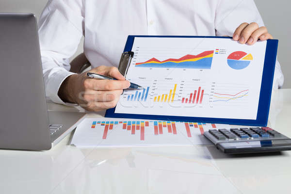 Businessman Showing Financial Charts At Desk Stock photo © AndreyPopov