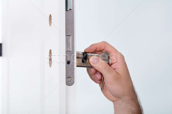 Man's Hand Installing Door Lock In Door Stock photo © AndreyPopov