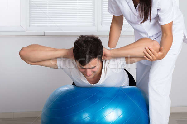 Physiotherapist Assisting Man While Doing Exercise Stock photo © AndreyPopov
