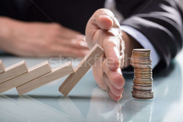 Human Hand Stopping Wooden Blocks From Falling On Stacked Coins Stock photo © AndreyPopov