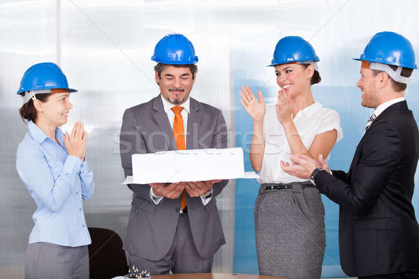 Stock photo: Colleagues Clapping For Man Holding Model