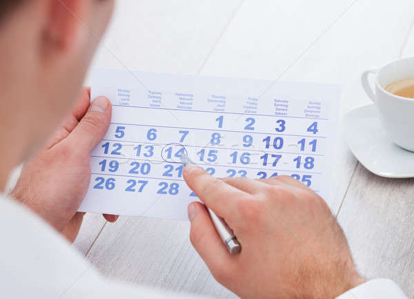 Man Marking With Pen And Looking At Date On Calendar Stock photo © AndreyPopov